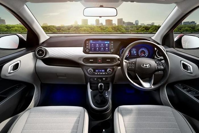 Bước vào bên trong Hyundai Grand i10 2023, người dùng sẽ có cảm giác quen thuộc vì cách bố trí của mẫu xe hatchback hạng A này về cơ bản là giống hệt như cũ. Tuy nhiên, hãng Hyundai cũng đã bổ sung chất liệu nỉ bọc ghế màu xám mới, vô lăng bọc da, hệ thống đèn dưới sàn đặt chân và tay nắm cửa bằng kim loại cho Grand i10 2023.